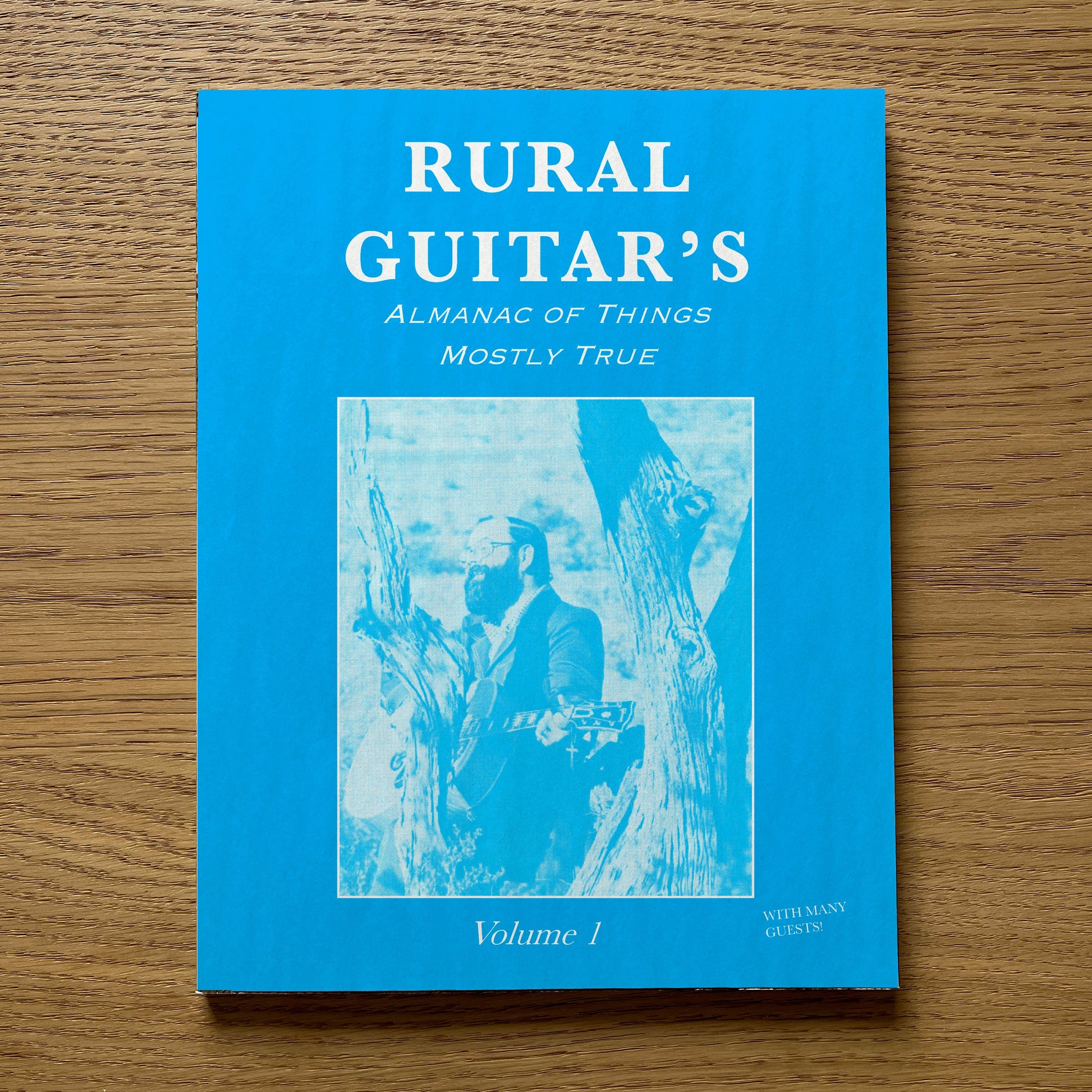 Blue book titled 'Rural Guitar's Almanac of Things Mostly True' on a wooden surface